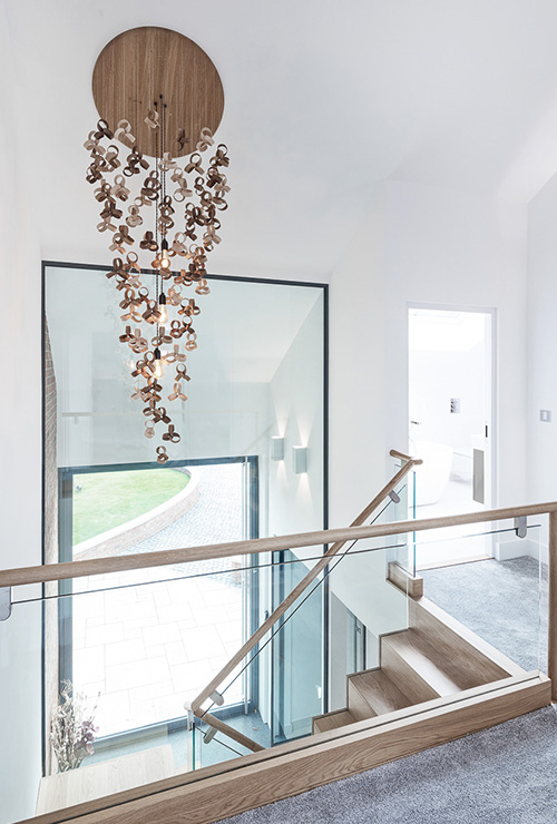 Top of staircase surrounded by large glass windows inside Ellingham Barns - a barn conversion project in Dorset, by INKSPACE Architects and Interior